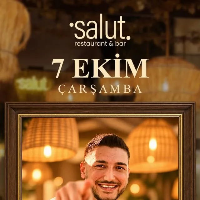 Salut Restaurant & Bar poster for 7 Ekim Çarşamba: Tunç Berk Sarı framed on a wooden picture frame under woven pendant lamps