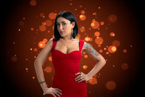 Kaya Hotels artist photo: Melek Mosso in a red dress against a dark red bokeh background