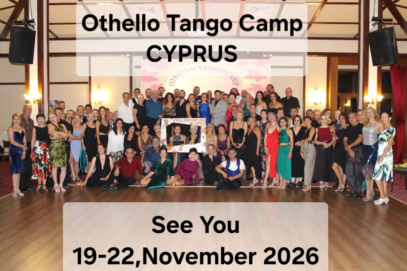 Othello Tango Camp Cyprus image: group photo of tango dancers on a wooden dance floor with 'See You 19-22, November 2026'