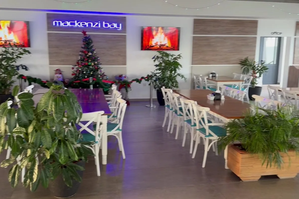 سالن Mackenzi Bay با صندلی‌های سفید، گیاهان و تابلوی نئون، تزئین‌شده برای کریسمس