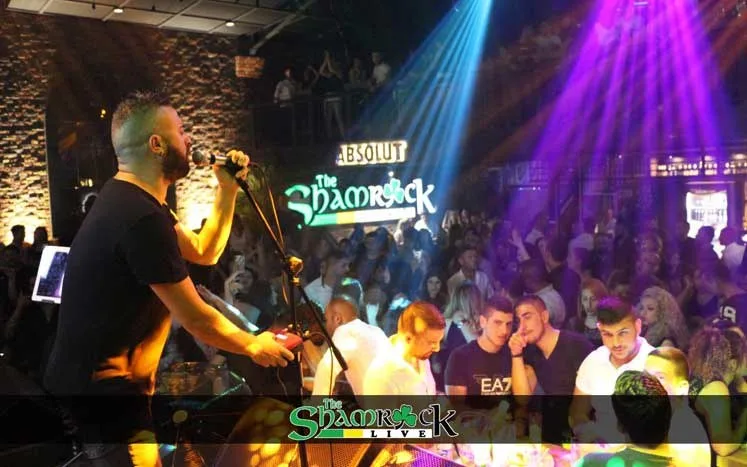 خواننده‌ای روی صحنه Shamrock Live در برابر جمعیتی انبوه زیر نورهای بنفش