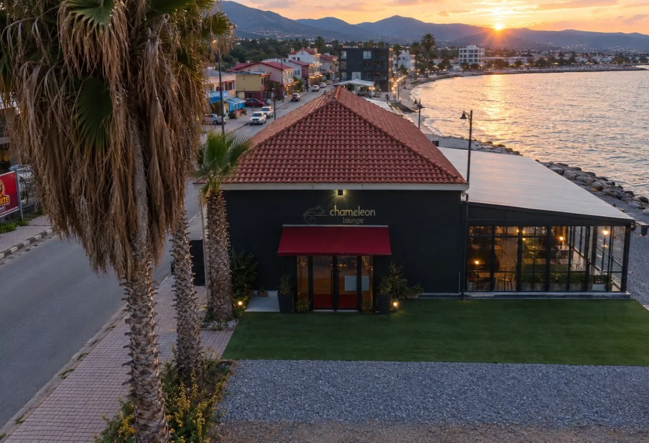 Chameleon Lounge at sunset: a dark building with a red tiled roof and glass terrace on the Gemikonağı seafront