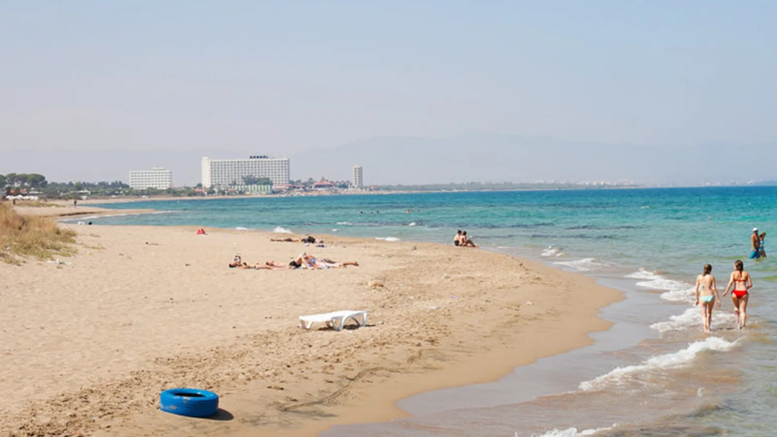 Sandy beach and turquoise sea at Bedi's Beach by Salamis, with hotels on the far shore