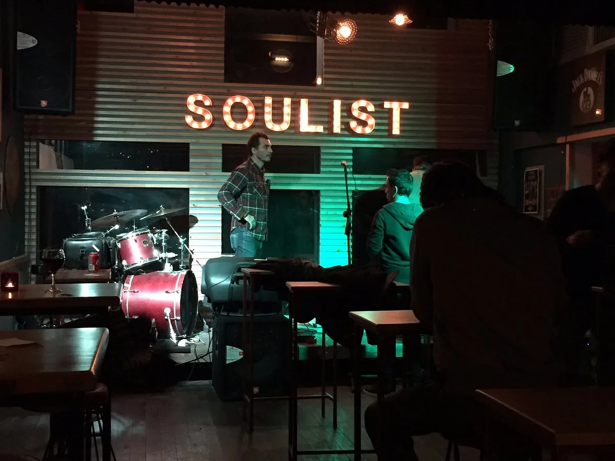 Stage at The Soulist in Alsancak, with a drum kit and the lit-up SOULIST marquee sign on a corrugated wall