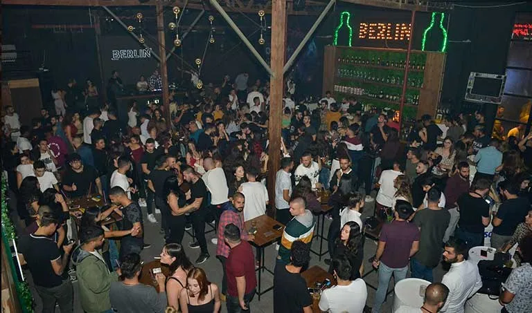 Berlin'de yüksek masalar ve neon Berlin tabelasıyla kalabalık salon