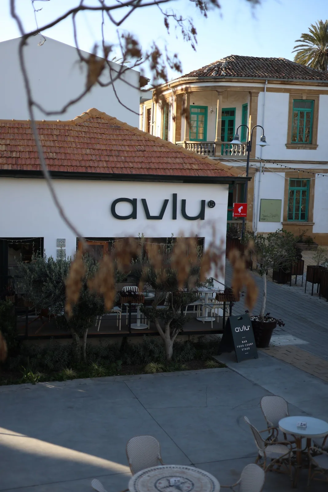 Avlu Nicosia's white building with the avlu sign, terrace tables and courtyard in Lefkoşa's old town