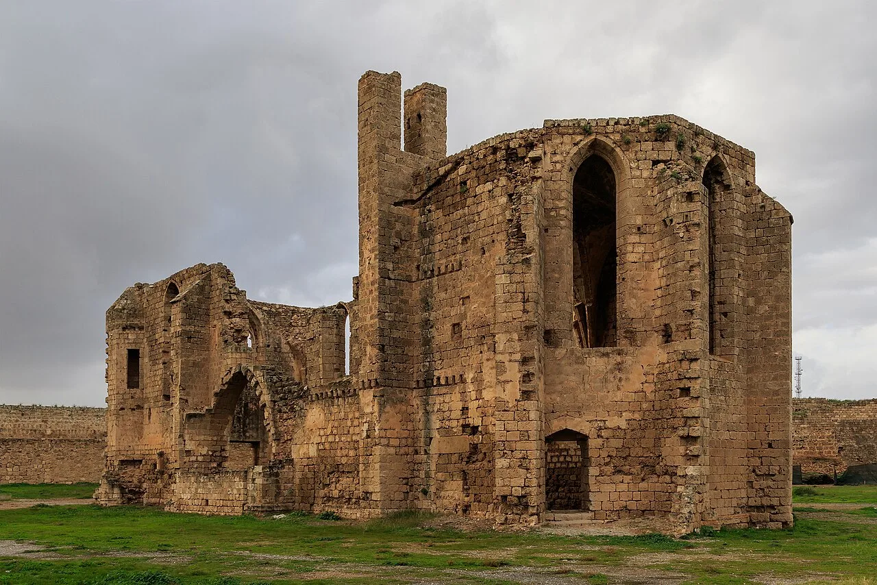 Roofless Gothic ruin of the Carmelite Church in Famagusta's walled city, tall stone walls with pointed windows under a cloudy sky