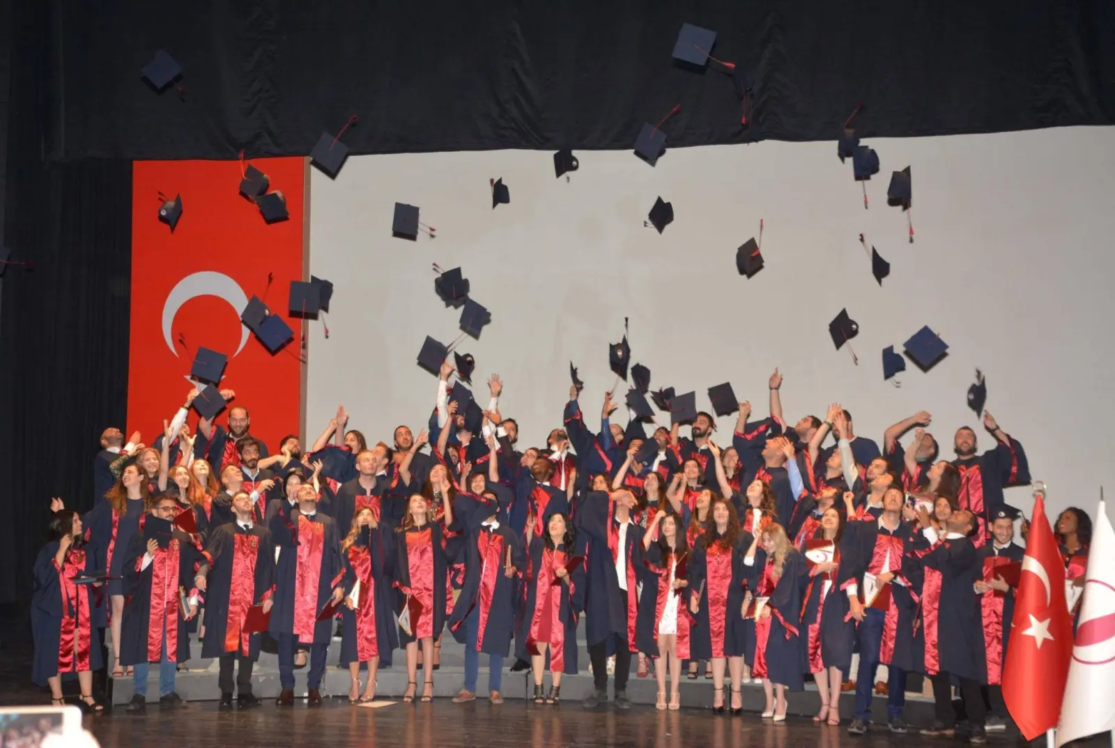 Graduates throwing their caps on the main hall stage of the Atatürk Culture and Congress Centre at Near East University, Nicosia